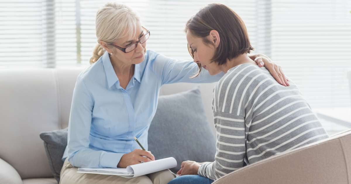 Counselor comforting client with hand on shoulder during a support session