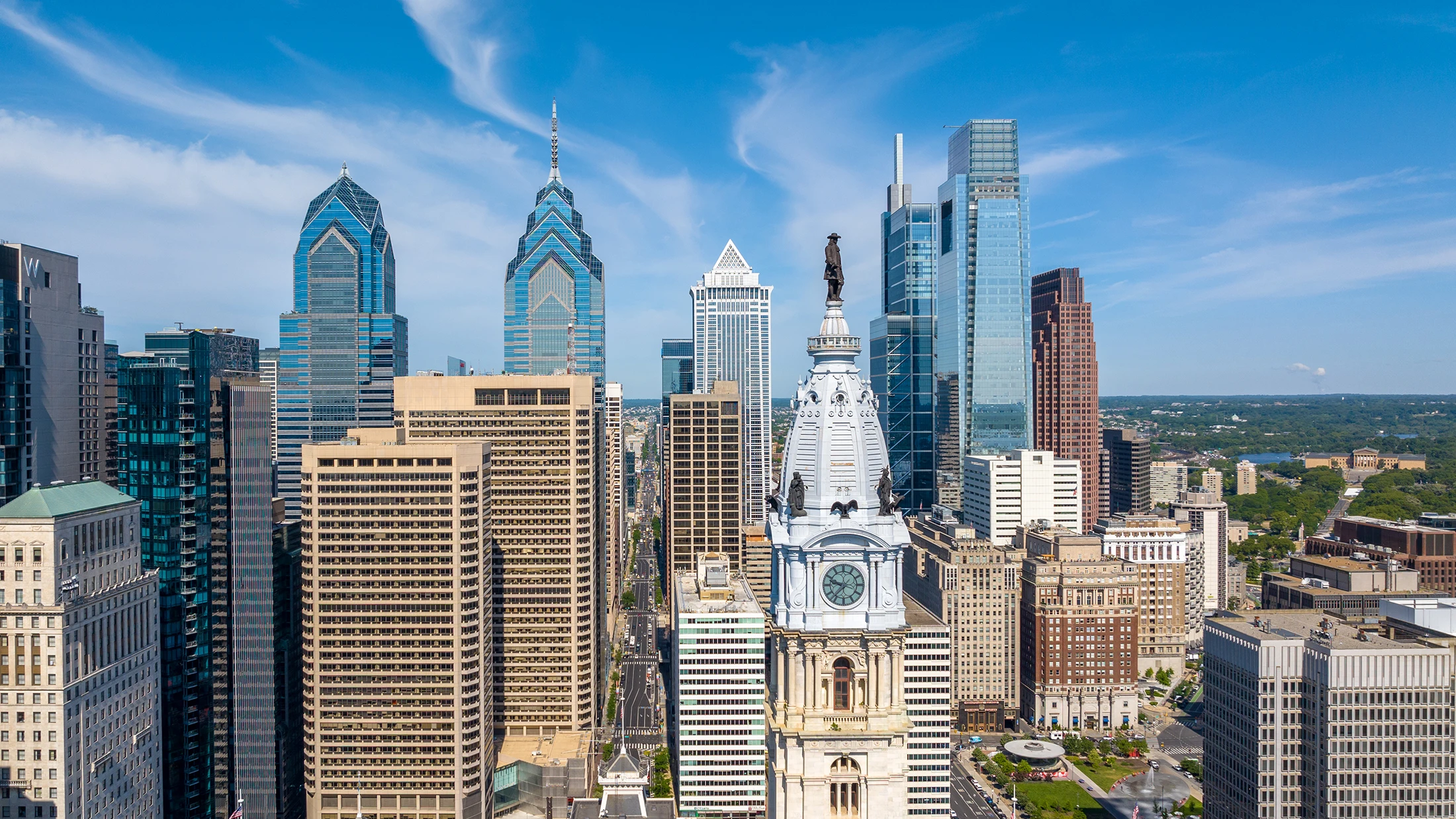 Downtown Philadelphia skyline with City Hall clock tower and skyscrapers under blue sky
