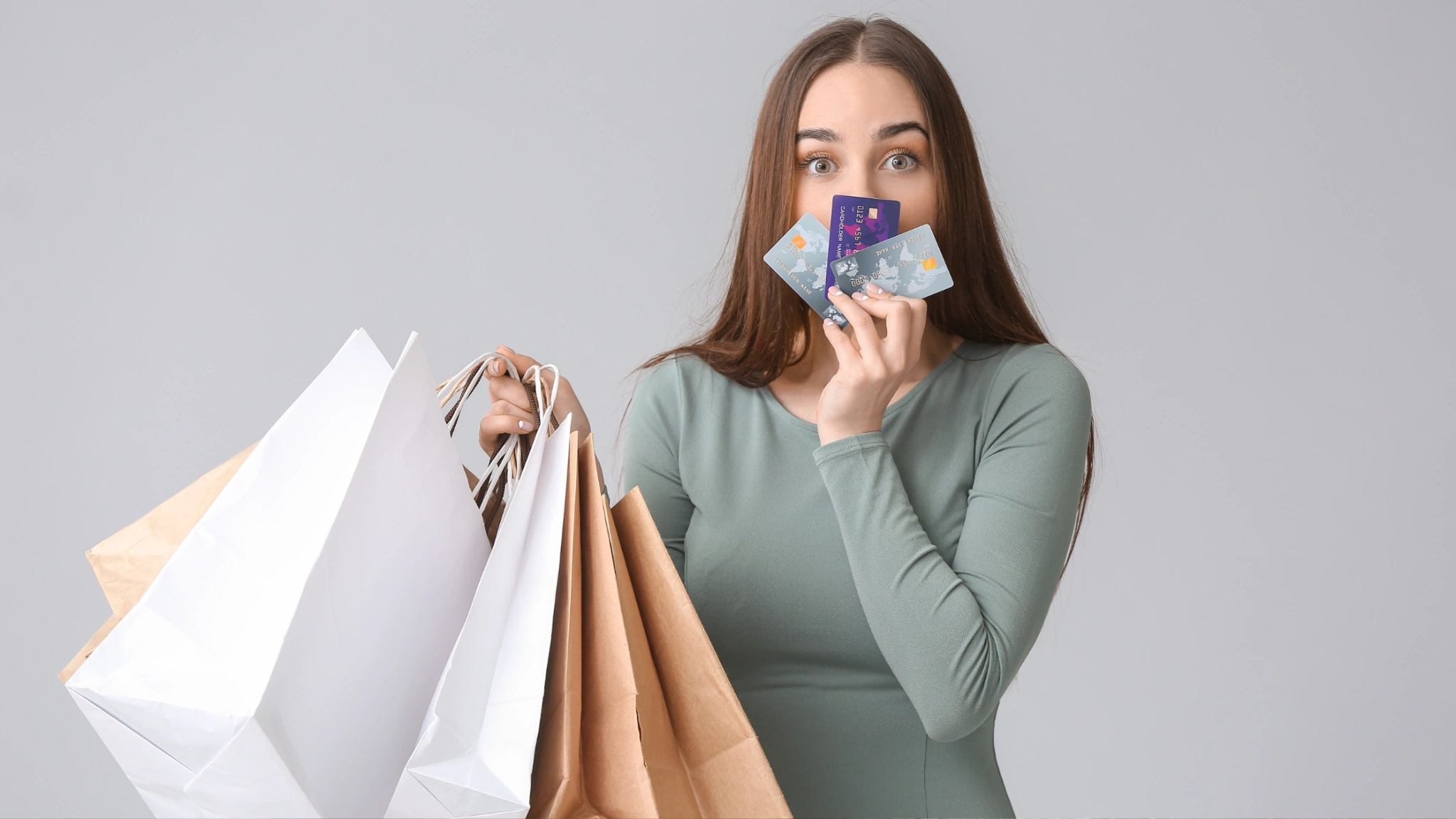 Woman holding shopping bags and credit cards representing impulsive spending behavior
