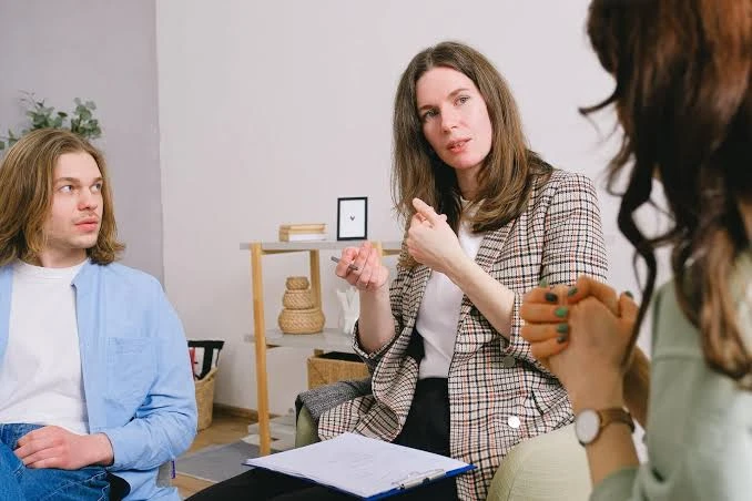 Counselor speaking with two clients during a therapy or consultation session